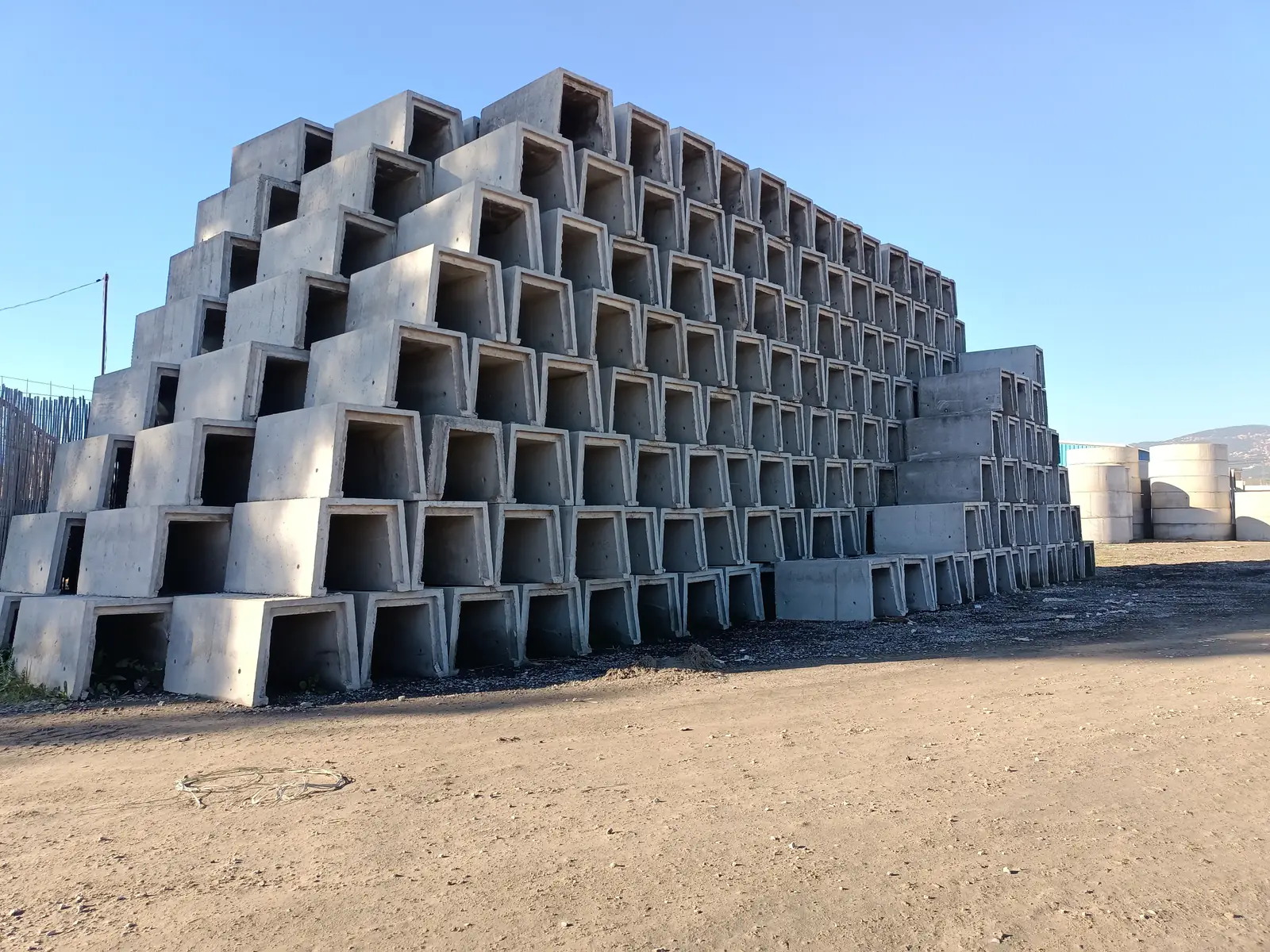 Caniveaux en béton FABP Sadoudi empilés en pyramide sur le parc de stockage, à Azazga