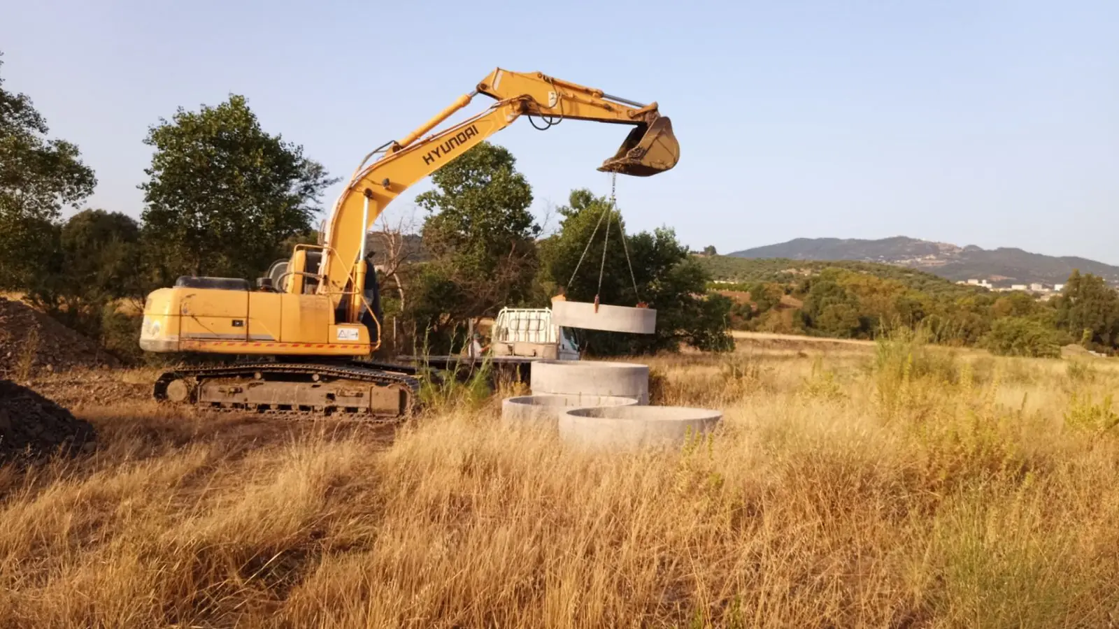 Pelle mécanique levant une buse armée pour puits sur le chantier